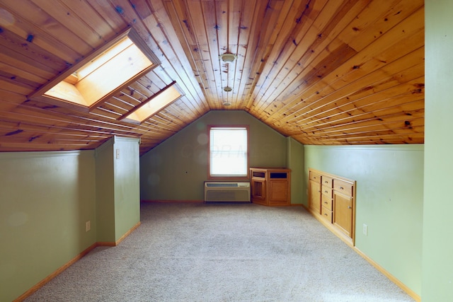 additional living space with vaulted ceiling with skylight, wood ceiling, a wall unit AC, and carpet flooring