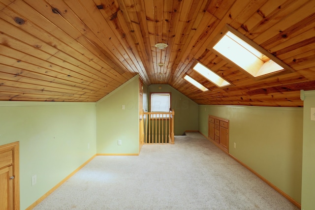 additional living space featuring light carpet, wooden ceiling, baseboards, and lofted ceiling with skylight