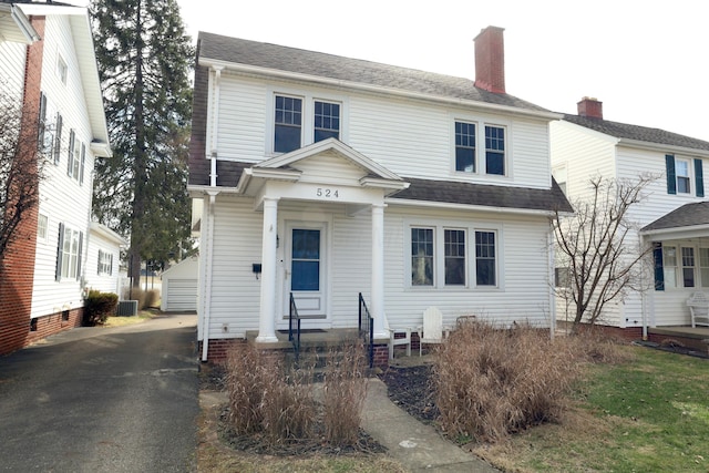 view of front of house featuring central AC, a shingled roof, an outdoor structure, driveway, and a chimney