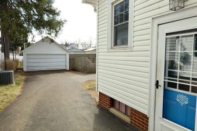 view of property exterior with a garage, an outdoor structure, fence, and central air condition unit