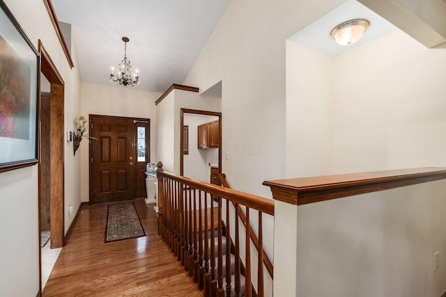 foyer entrance featuring vaulted ceiling, a chandelier, and light wood-style flooring