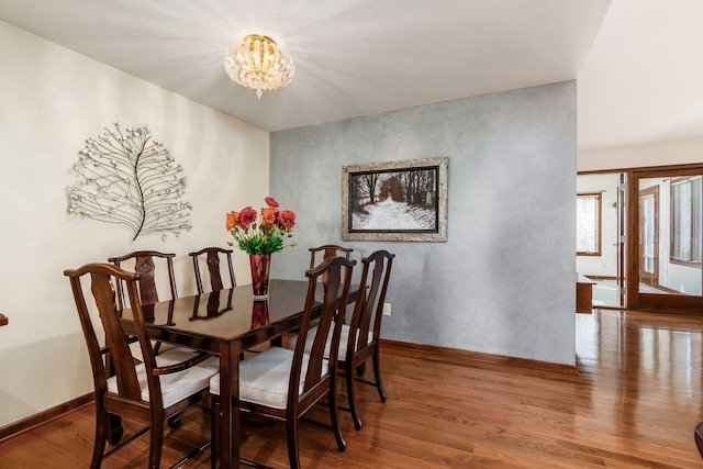 dining room featuring a chandelier, baseboards, and wood finished floors