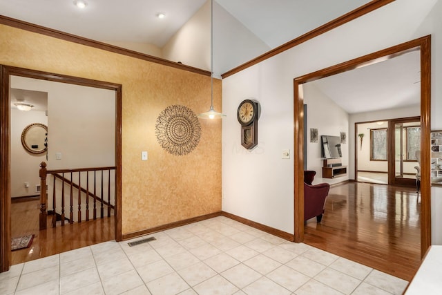 interior space with lofted ceiling, light wood-style flooring, an upstairs landing, visible vents, and baseboards