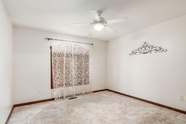 carpeted spare room with a ceiling fan and baseboards