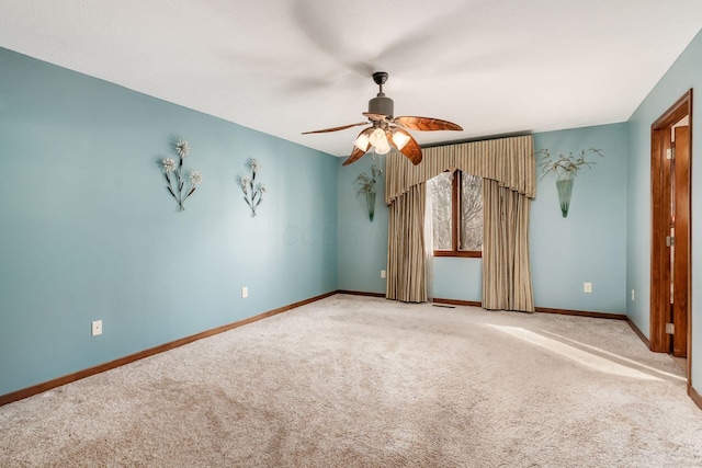 carpeted spare room with a ceiling fan and baseboards