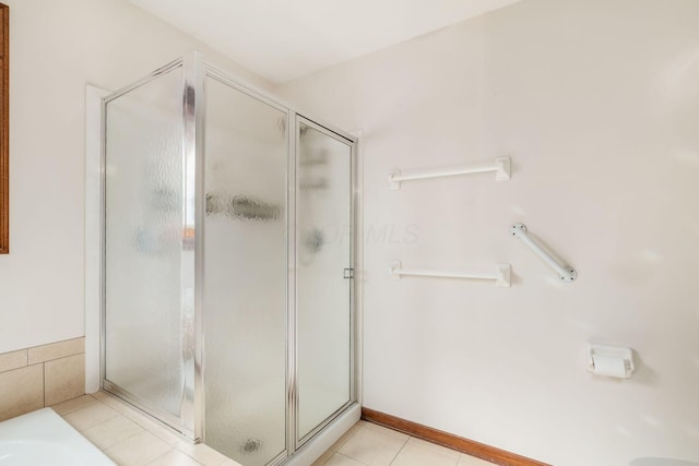 bathroom featuring a stall shower, tile patterned flooring, and a washtub