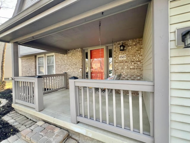 doorway to property with brick siding and covered porch