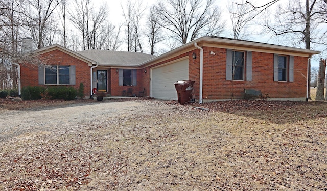 ranch-style home featuring brick siding, driveway, a chimney, and an attached garage