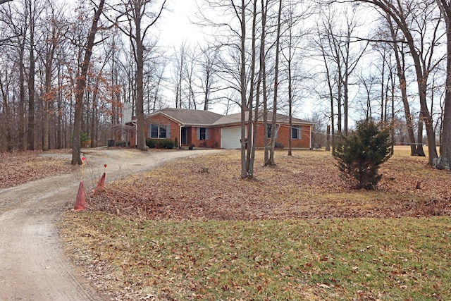 ranch-style house featuring a garage, brick siding, and dirt driveway