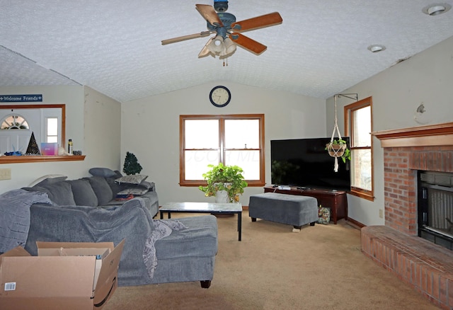 carpeted living area with vaulted ceiling, a textured ceiling, a fireplace, and a ceiling fan