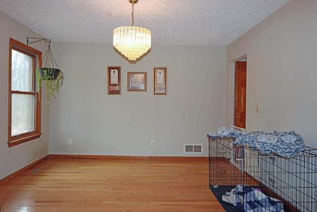 dining area with a chandelier, light wood finished floors, a textured ceiling, and visible vents