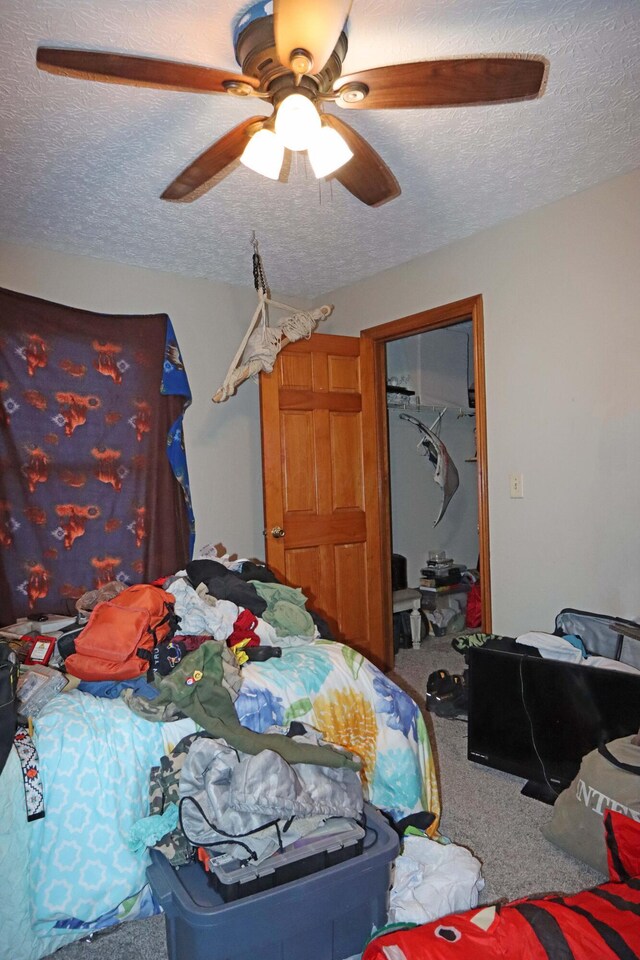 carpeted bedroom with a ceiling fan and a textured ceiling