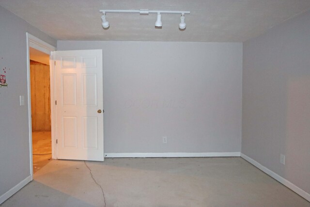 empty room with concrete flooring and baseboards