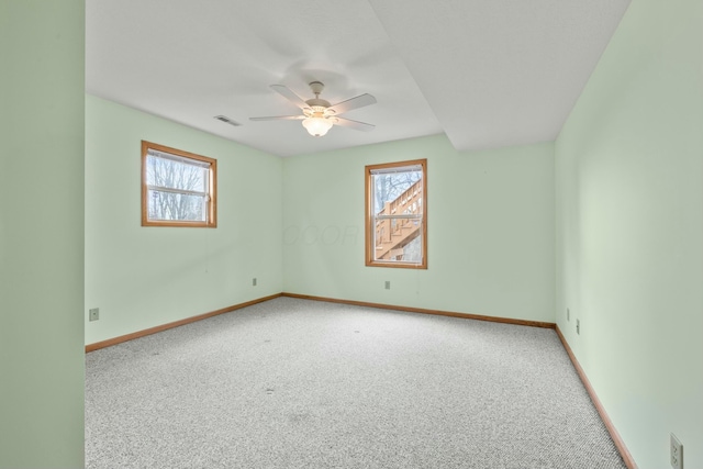 empty room with carpet, visible vents, and plenty of natural light