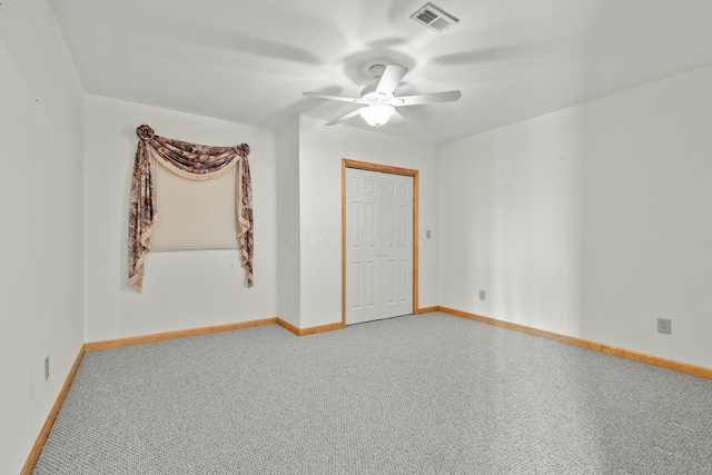 carpeted spare room with baseboards, visible vents, and a ceiling fan