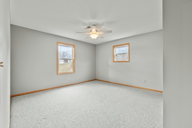 unfurnished room with baseboards, a ceiling fan, visible vents, and a healthy amount of sunlight