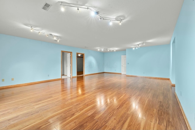 empty room with visible vents, light wood-style flooring, and baseboards