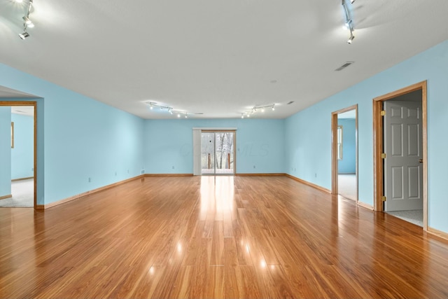 unfurnished room featuring baseboards, visible vents, light wood-style flooring, and track lighting