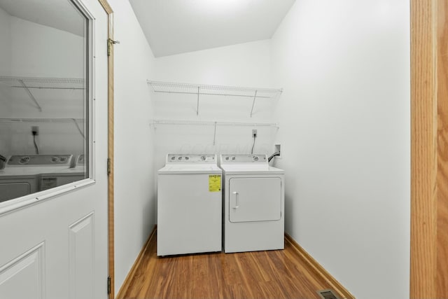 laundry room featuring laundry area, visible vents, baseboards, wood finished floors, and independent washer and dryer