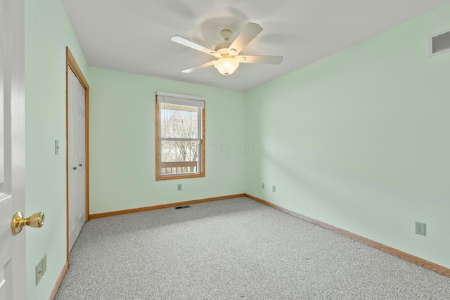 empty room featuring a ceiling fan, carpet, visible vents, and baseboards