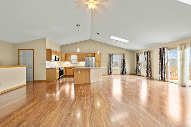 unfurnished living room with light wood-type flooring, lofted ceiling with skylight, baseboards, and a ceiling fan