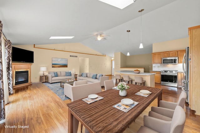 151 Heatherwood Dr, Howard, OH 43028 - dining area with light wood-style floors, a skylight, lofted ceiling, a glass covered fireplace, and ceiling fan