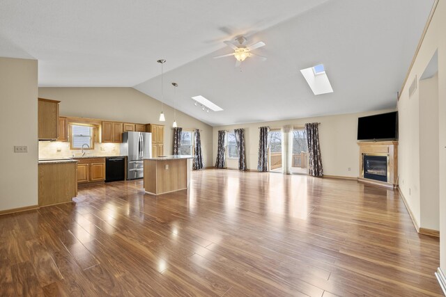 151 Heatherwood Dr, Howard, OH 43028 - unfurnished living room with a skylight, vaulted ceiling, dark wood-type flooring, ceiling fan, and a glass covered fireplace