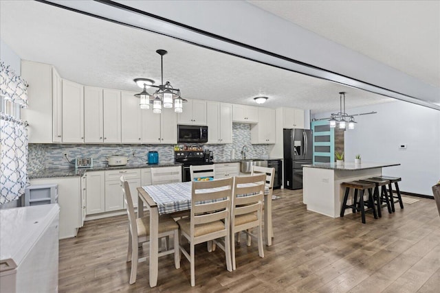 kitchen featuring electric stove, light wood-style floors, white cabinetry, a kitchen island, and stainless steel fridge with ice dispenser