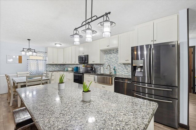 kitchen featuring appliances with stainless steel finishes, white cabinets, a sink, and backsplash