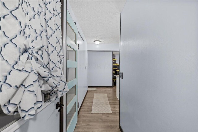 corridor featuring a textured ceiling and wood finished floors