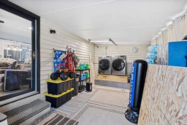 laundry area with a garage, laundry area, independent washer and dryer, and wood walls