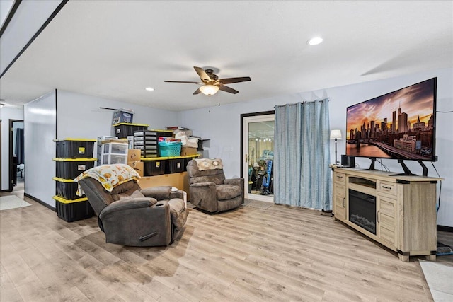 living room with baseboards, ceiling fan, light wood-style floors, a fireplace, and recessed lighting