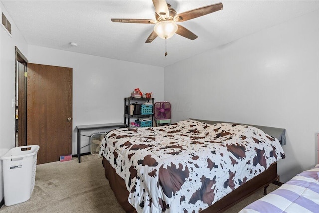 carpeted bedroom with a ceiling fan and a textured ceiling