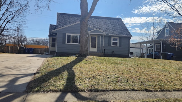 view of front facade featuring roof with shingles, a front yard, and fence