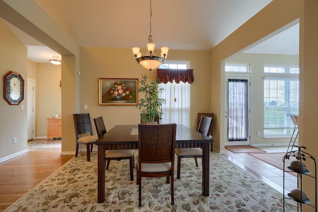 dining room featuring light wood-type flooring, baseboards, and a notable chandelier