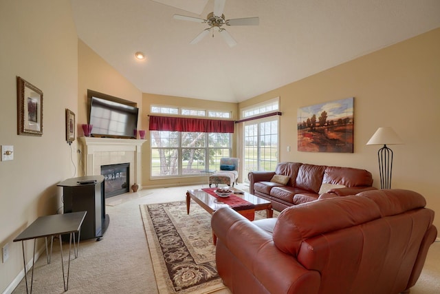 living room with ceiling fan, high vaulted ceiling, a tile fireplace, and light colored carpet