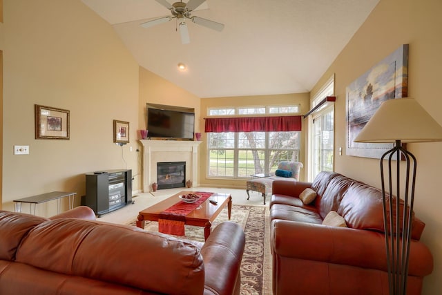 carpeted living room with high vaulted ceiling, a glass covered fireplace, and a ceiling fan