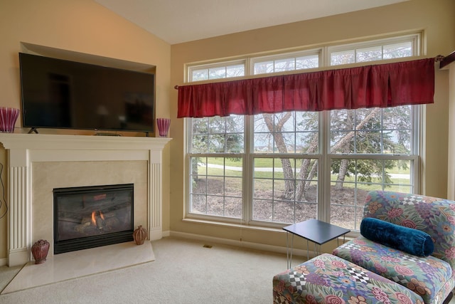 living area featuring carpet floors, baseboards, vaulted ceiling, and a glass covered fireplace