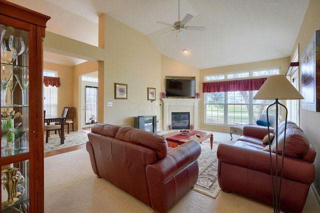 living room with ceiling fan, high vaulted ceiling, and a glass covered fireplace