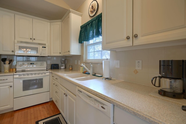 kitchen with white cabinets, white appliances, light wood finished floors, and a sink