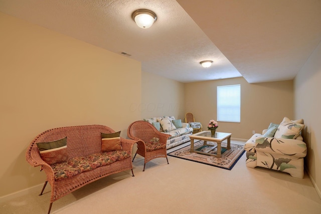 living room featuring carpet, visible vents, a textured ceiling, and baseboards