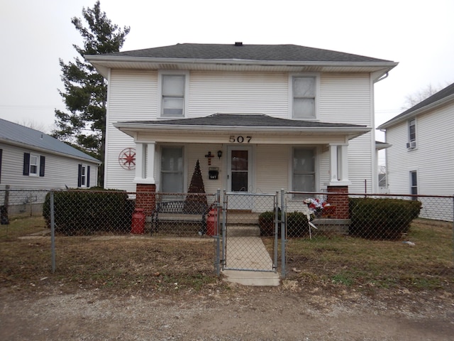 american foursquare style home with a porch, a gate, and a fenced front yard