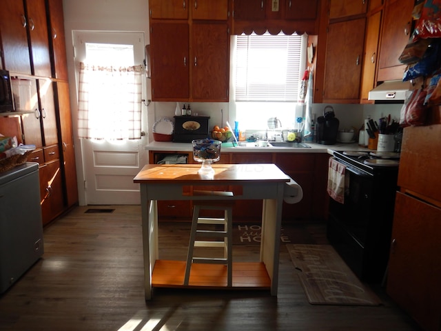 kitchen with a sink, under cabinet range hood, black range with electric cooktop, and light countertops