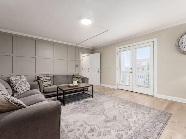 living room featuring light wood-type flooring, ornamental molding, a decorative wall, and french doors