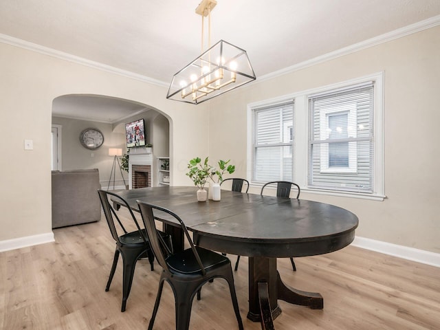 dining room featuring light wood-style floors, a fireplace, and arched walkways