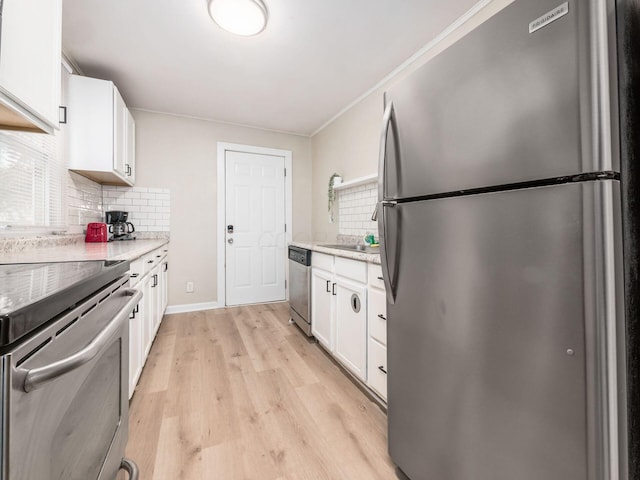 kitchen featuring white cabinetry, ornamental molding, appliances with stainless steel finishes, backsplash, and light wood finished floors