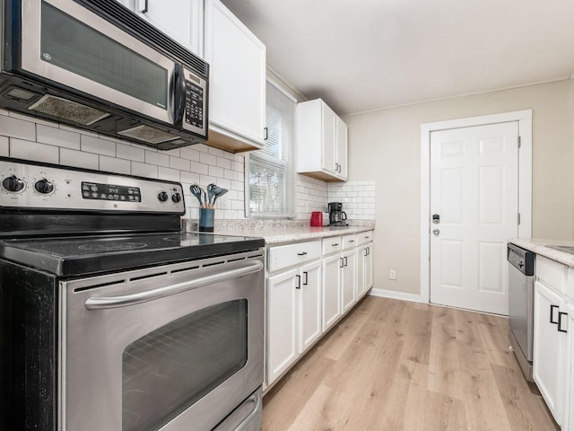 kitchen with white cabinets, light wood-type flooring, stainless steel appliances, and backsplash