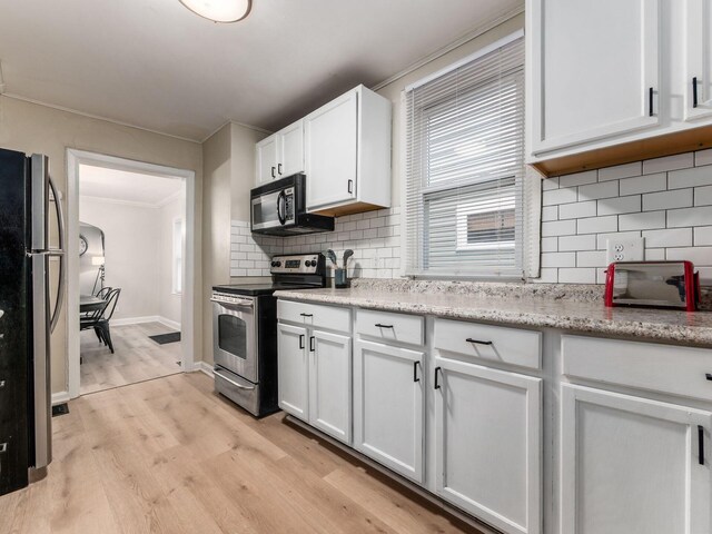 kitchen with white cabinetry, ornamental molding, appliances with stainless steel finishes, light wood-type flooring, and backsplash