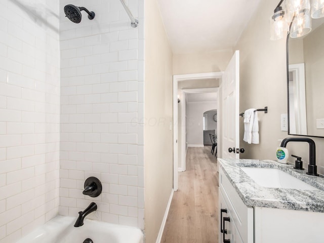 bathroom featuring shower / washtub combination, vanity, baseboards, and wood finished floors