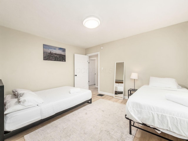 bedroom with light wood finished floors, visible vents, and baseboards